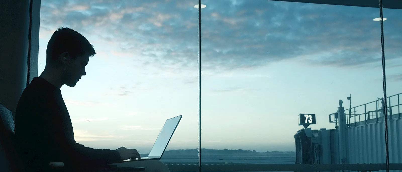 Traveler working on a laptop beside an airport window
